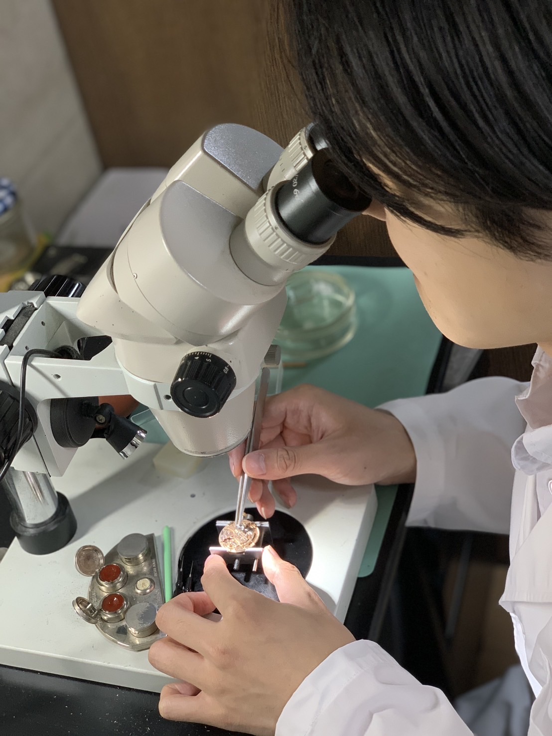 顕微鏡を使って時計を修理する職人